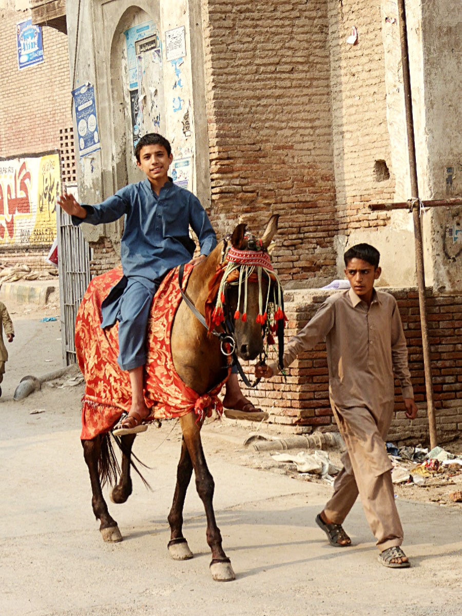 Child on a horse and another child is leading the horse in the City of Peshawar.